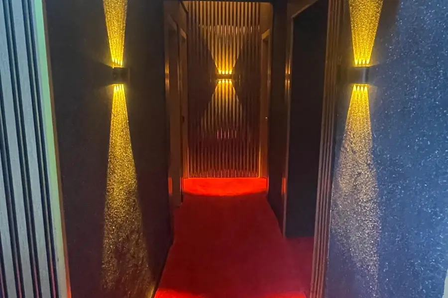 Duvar lambalarıyla aydınlanan kırmızı halılı koridor